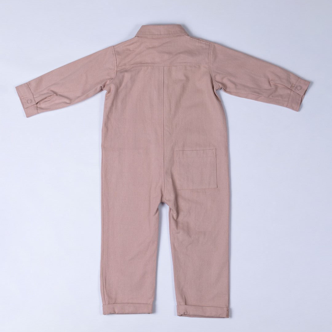 Rear view of the dusty pink cotton denim boilersuit with Aneby hem tag