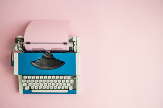 Antique typewriter against a pink background