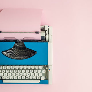 Antique typewriter against a pink background