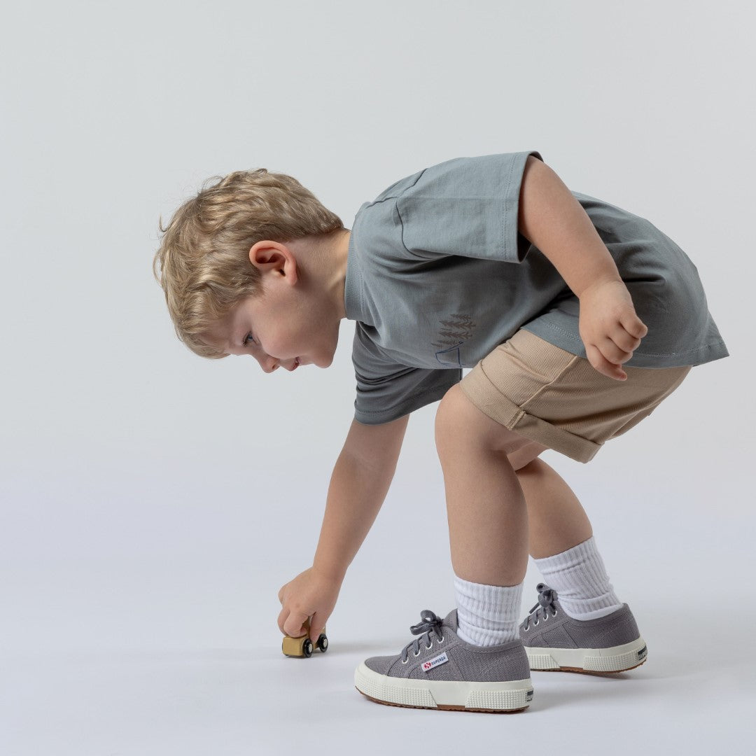 Model playing with a toy car, wearing Aneby t-shirt and shorts