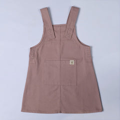 Pastel pink dungaree dress with dyed to match poppers and front pocket featuring the Aneby hem tag