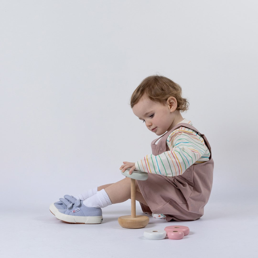 Small girl wearing dungaree dress playing with wooden toy