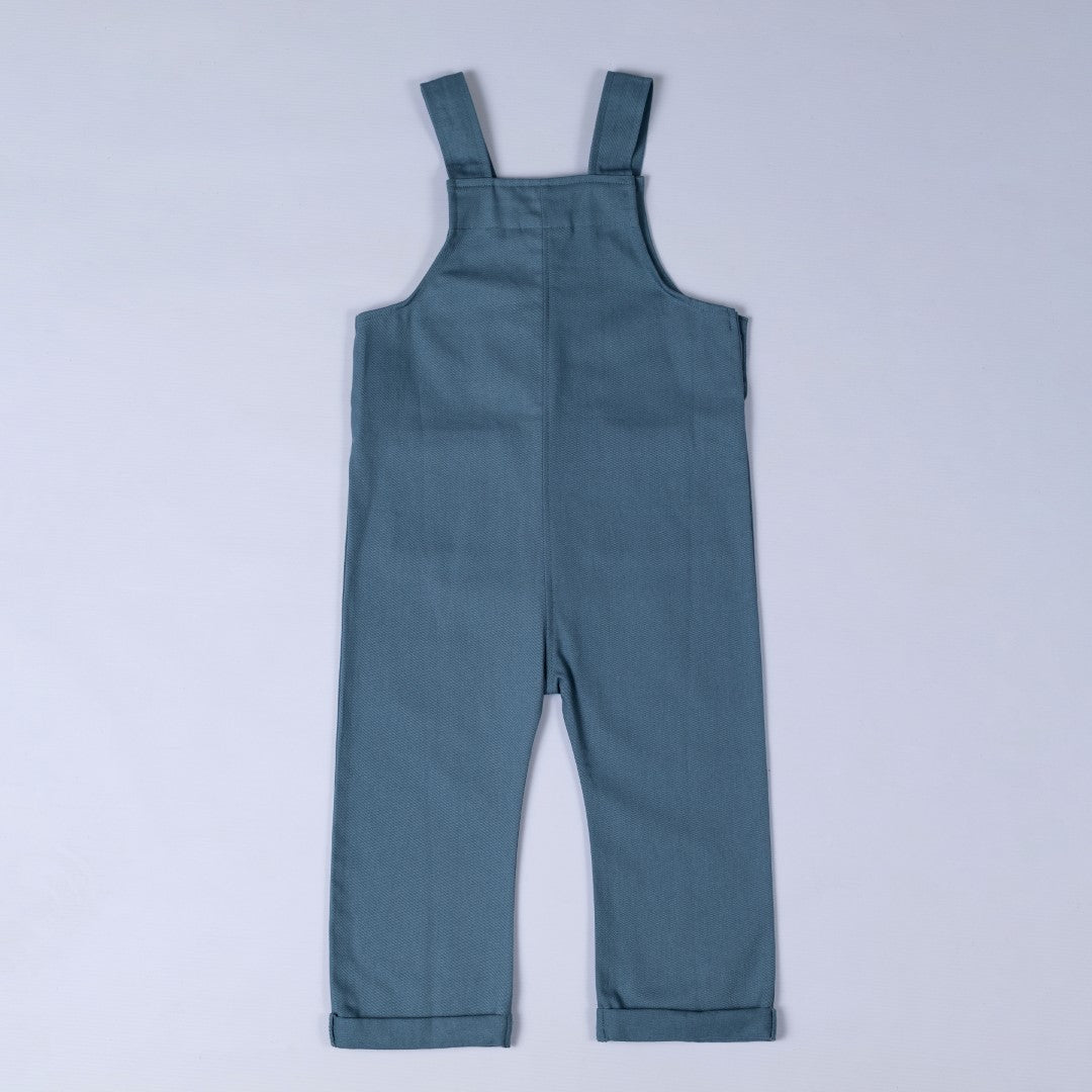 Rear view of steel blue dungarees with shoulder straps and rolled hem