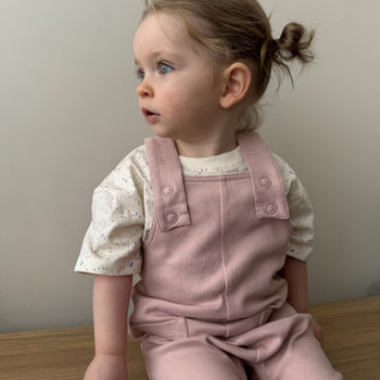 Girl Sitting in Pink Dungarees