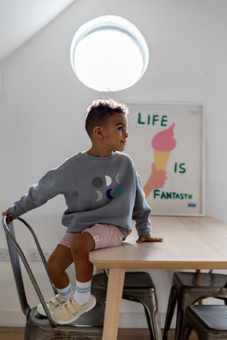 Young model sitting on a table with the words "life is fantastic" in the background with a hand drawn picture of an ice cream cone