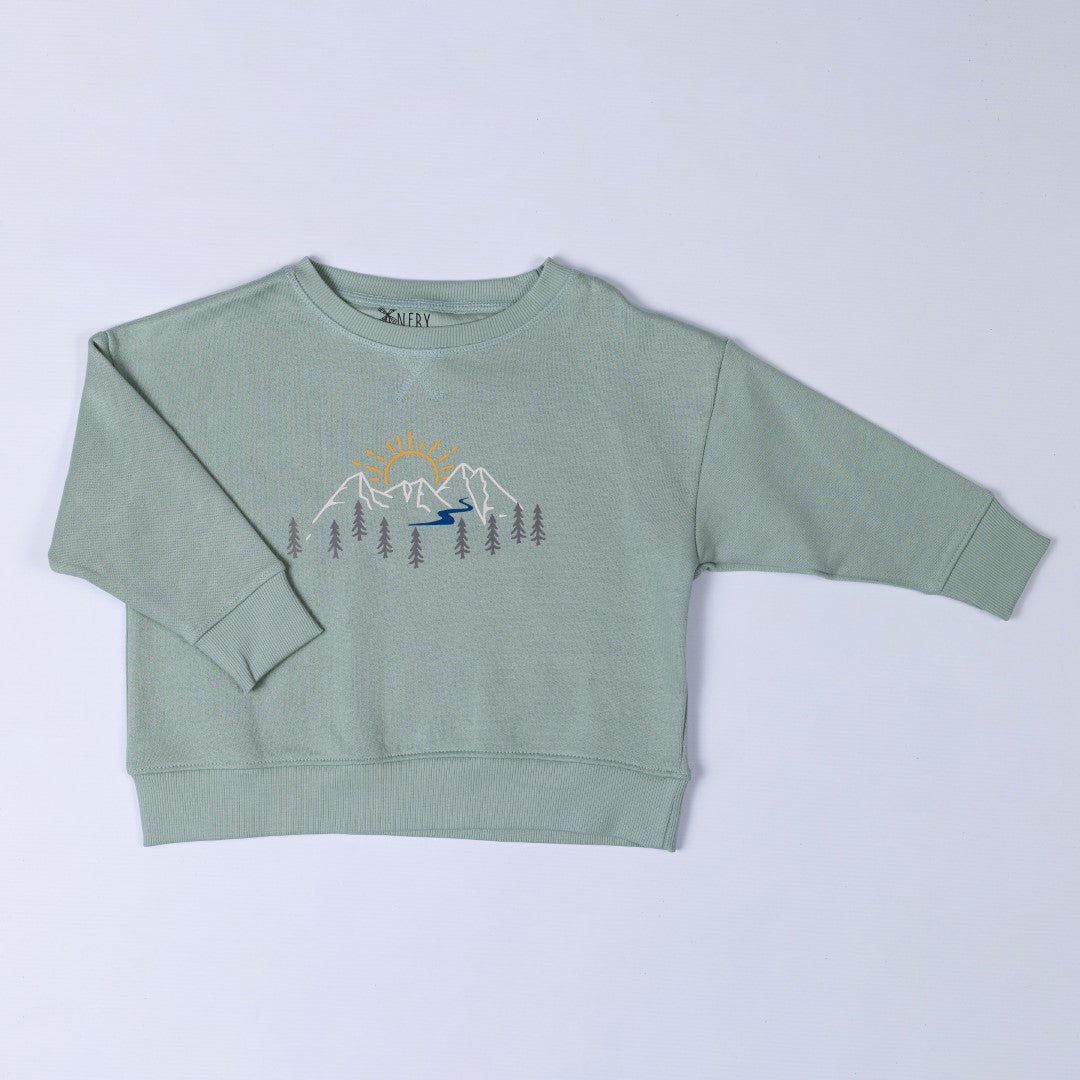 Product photo of the sage green Aneby sweatshirt with mountain adventure design featuring pine trees, rivers and sun-rises