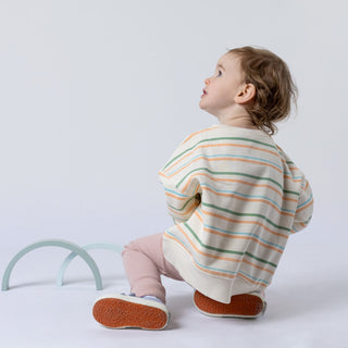 Striped sweatshirt from Aneby being modelled by young girl who is looking off into the distance whilst playing with wooden toy prop