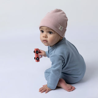 Small girl sitting on floor with toy car in hand modelling the blue Aneby jumpsuit