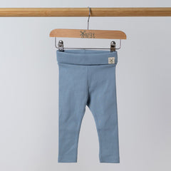 Slate blue baby leggings with rolled waistband and windmill hem tag hanging on rail