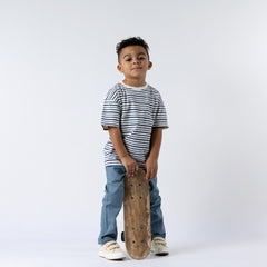 Model wearing striped t-shirt holding a skateboard