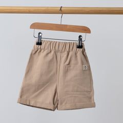 Rear view of oat Aneby shorts on wooden hanger with rolled hem and elasticated waist band