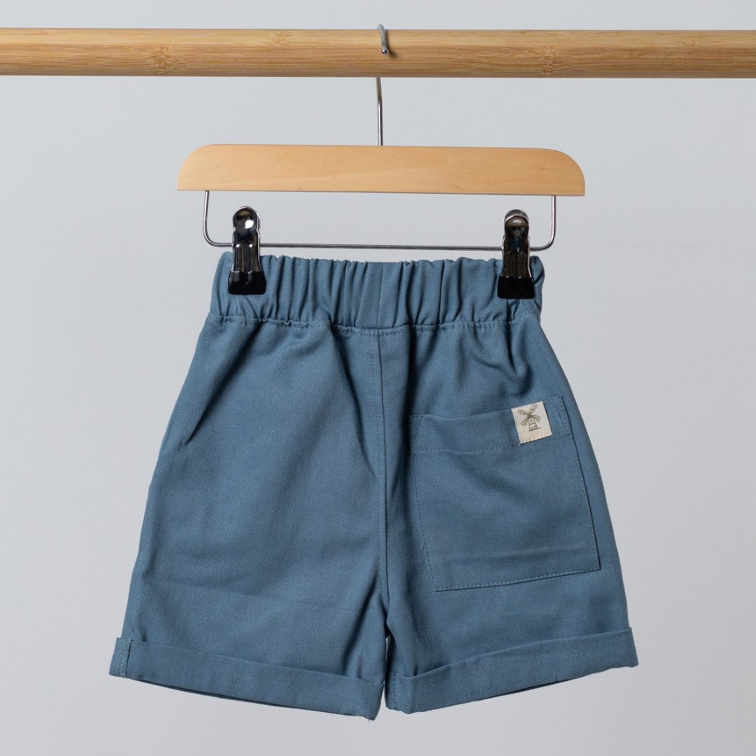 Blue Aneby shorts handing from wooden frame with windmill hem tag in close view