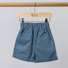 Front view of Blue Aneby shorts handing from wooden frame with pockets and rolled hem