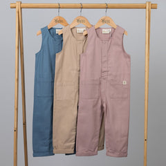 Sleeveless jumpsuits hanging from wooden frame in blue, beige and pink