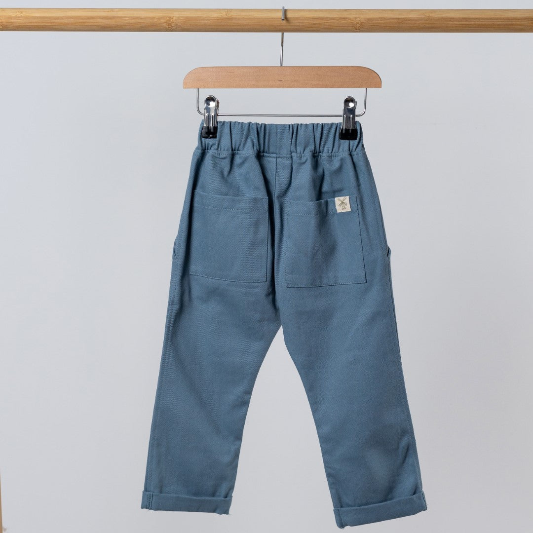 Rear view of Slate blue trousers with elasticated waist hanging from wooden clothes hanger