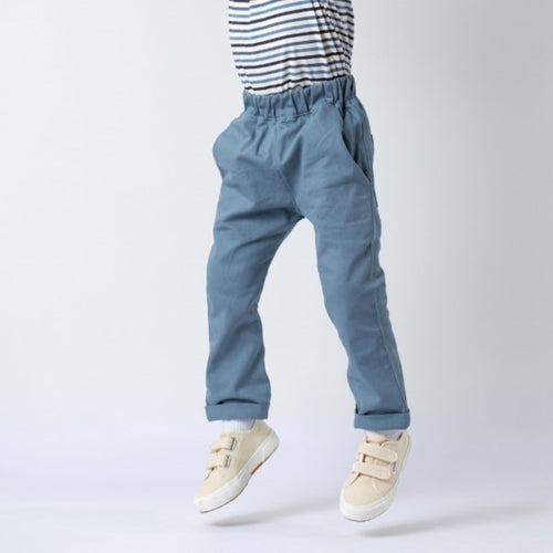 Boy wearing blue trousers and a striped t-shirt, jumping in the air