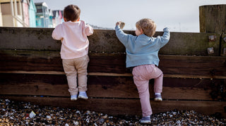 Two Aneby models looking over the sea wall with beach huts off into the distance