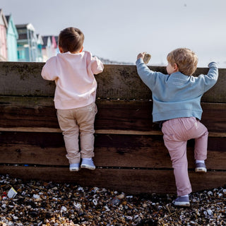 Two Aneby models looking over the sea wall with beach huts off into the distance