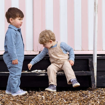 Two Boys in Front Of Pink Beach Hut Wearing Dungarees