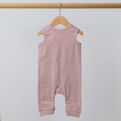 Dusty pink sleeveless rib baby romper hanging on a wooden frame, back view. Neutral background.