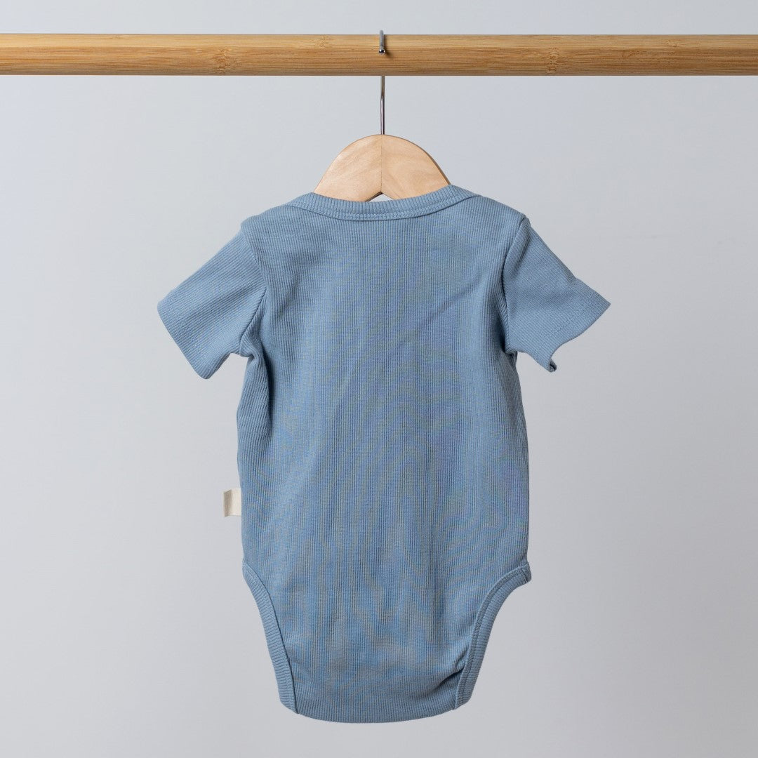 Slate blue short sleeve baby bodysuit shown from the back on a wooden hanger.