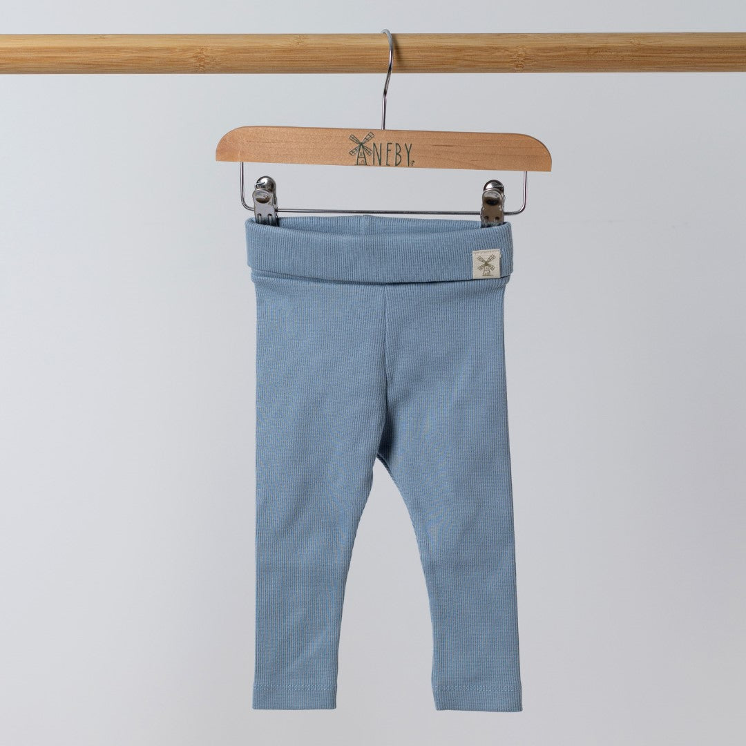 Front view of organic blue ribbed baby leggings with the Aneby hem tag visible on the waistband, hanging from a wooden Aneby clothes hanger