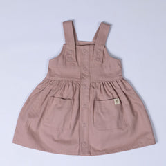 Flat lay of a dusty pink girls’ pleated dress with straps, highlighting the soft pleats and structured yet comfortable fit.