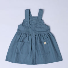 Flat lay of a slate blue girls’ pleated dress with straps, carefully positioned to showcase the front design and smooth pleated skirt.