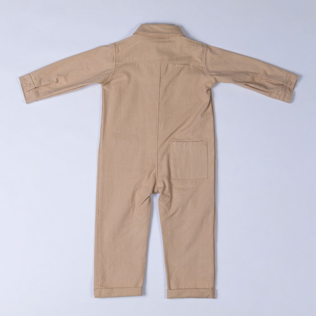 Back view of an oat-coloured twill kids boilersuit, showing its relaxed fit and stitching details.