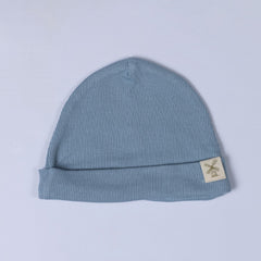 A slate blue kids ribbed cotton beanie hat with a fold-over cuff and a woven logo label, displayed on a white background.