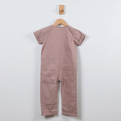 Dusty pink short sleeve overall hanging on a wooden hanger with a back view in a neutral background.