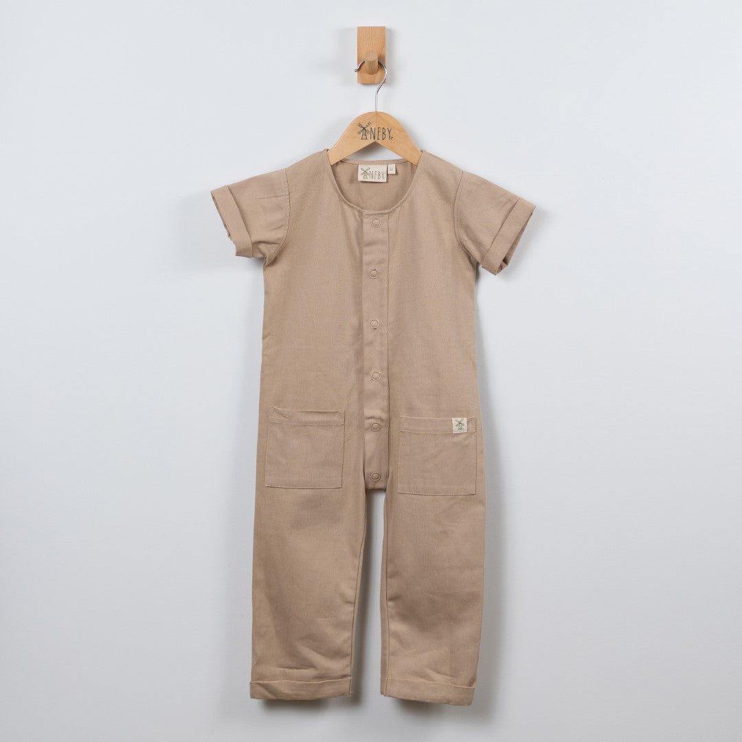 Beige short sleeve overall hanging on a wooden hanger with a front view in a neutral background.