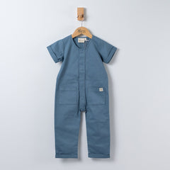 Slate blue short sleeve overall hanging on a wooden hanger with a front view in a neutral background.