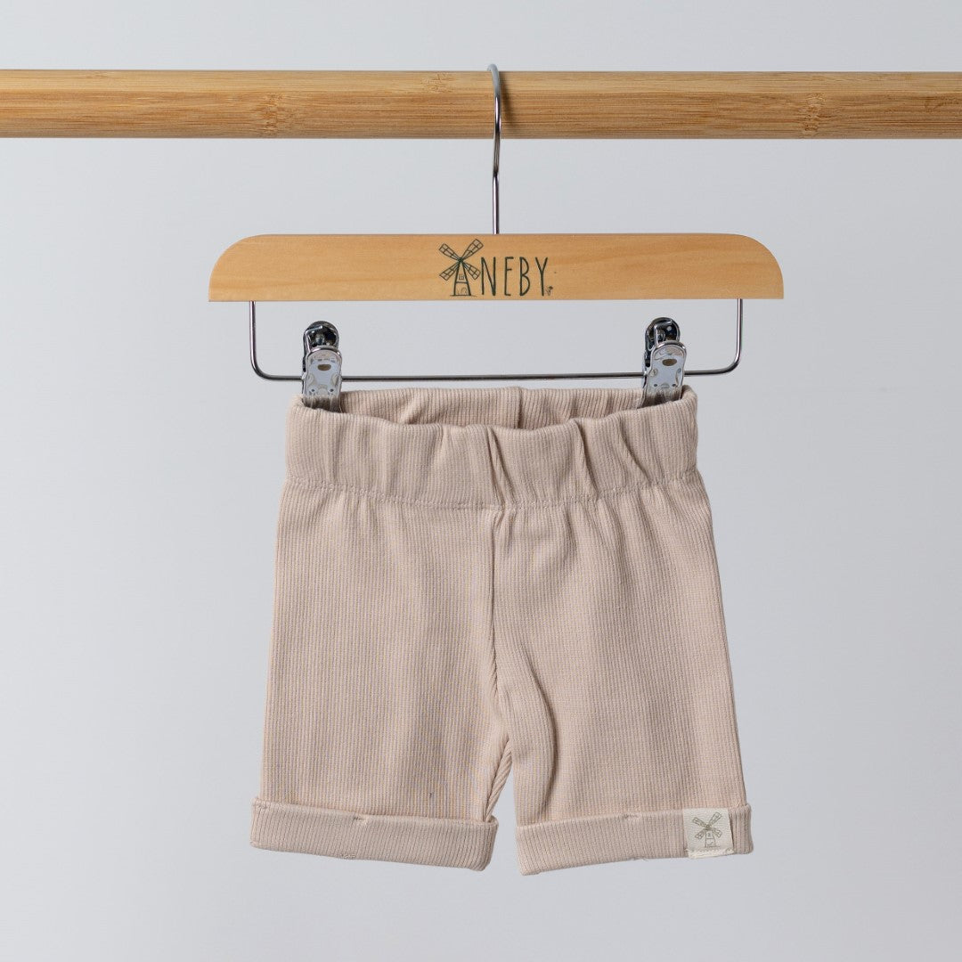 Front view of oat ribbed organic cotton kids shorts hanging on a wooden hanger, with neutral background.