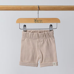 Front view of oat ribbed organic cotton kids shorts hanging on a wooden hanger, with neutral background.
