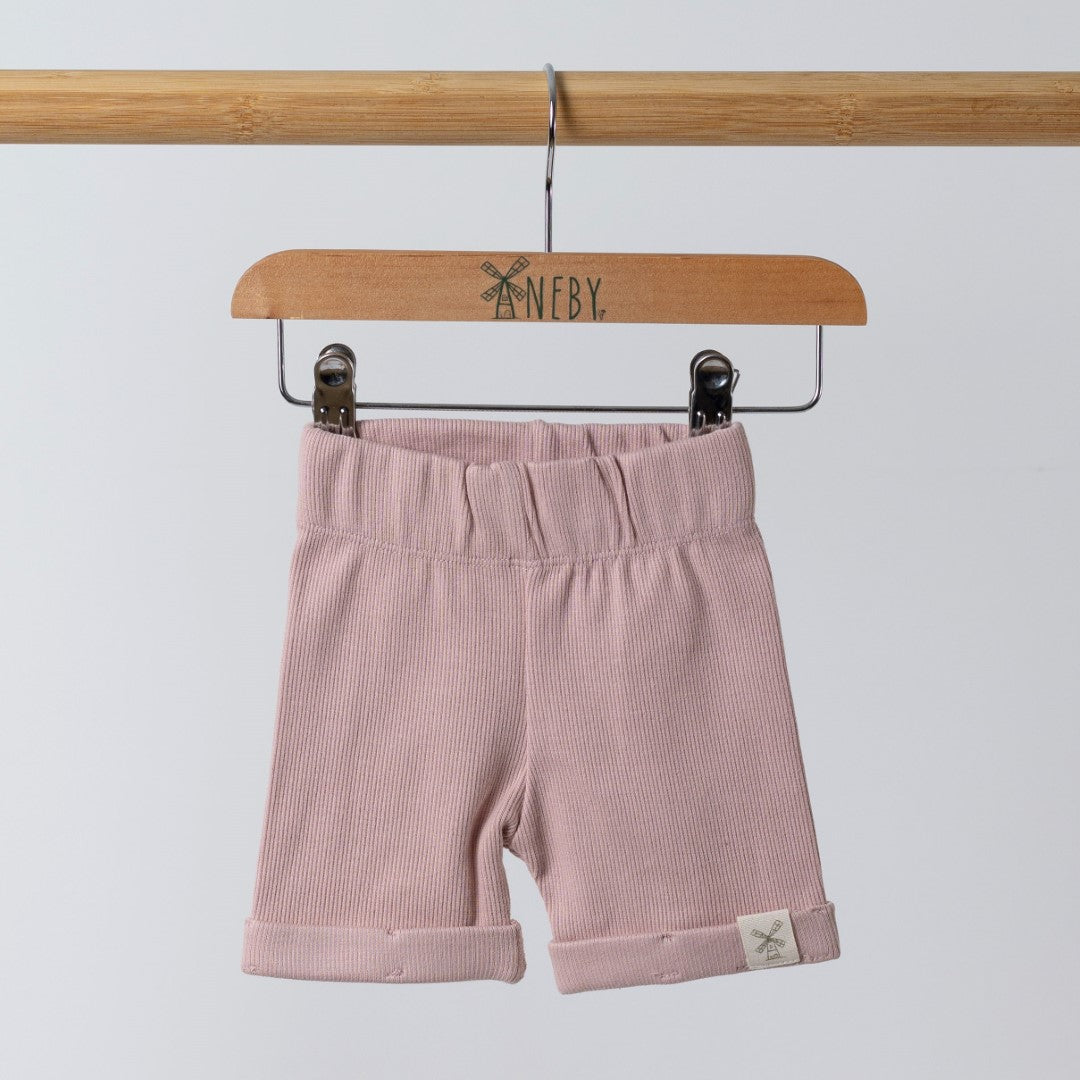 Front view opink ribbed organic cotton kids shorts hanging on a wooden hanger, with neutral background.