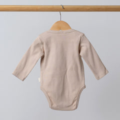 Back view of an oat-coloured ribbed bodysuit with long sleeves for babies, hanging on a wooden hanger.