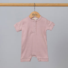 Dusty pink short sleeve rib baby romper hanging, front view.